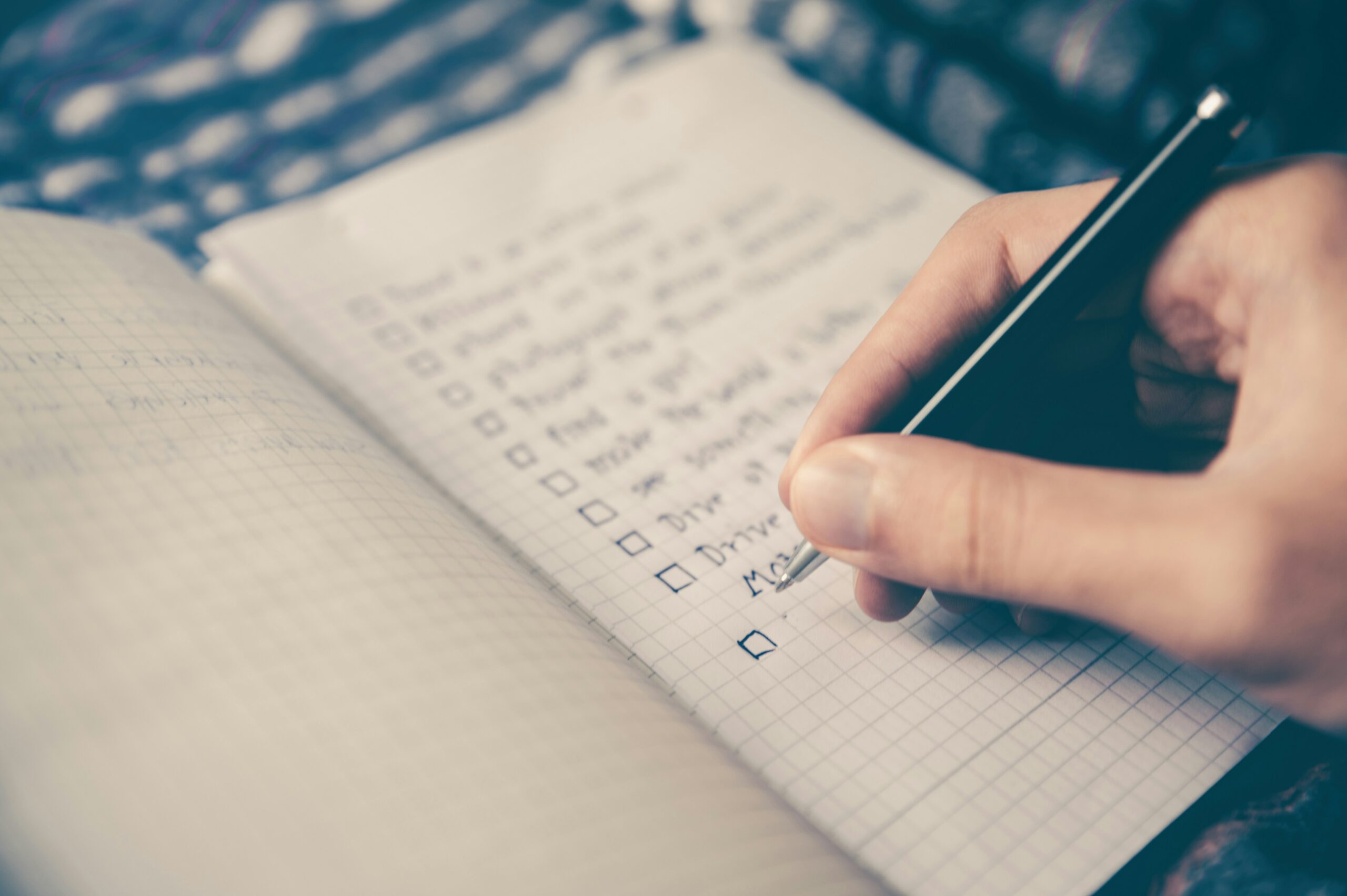 A close-up of a person writing a checklist in a notebook, marking off completed tasks as part of goal-setting and planning.