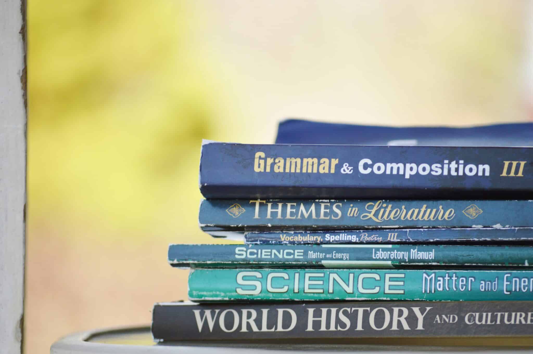 A stack of textbooks covering Grammar, Literature, Science and History — representing the different subject pathways VCE students weigh when choosing their English subject