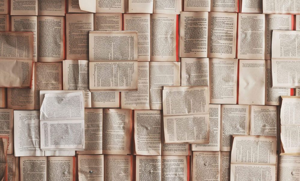 A collection of open books arranged in a grid-like pattern, with pages displaying various texts.