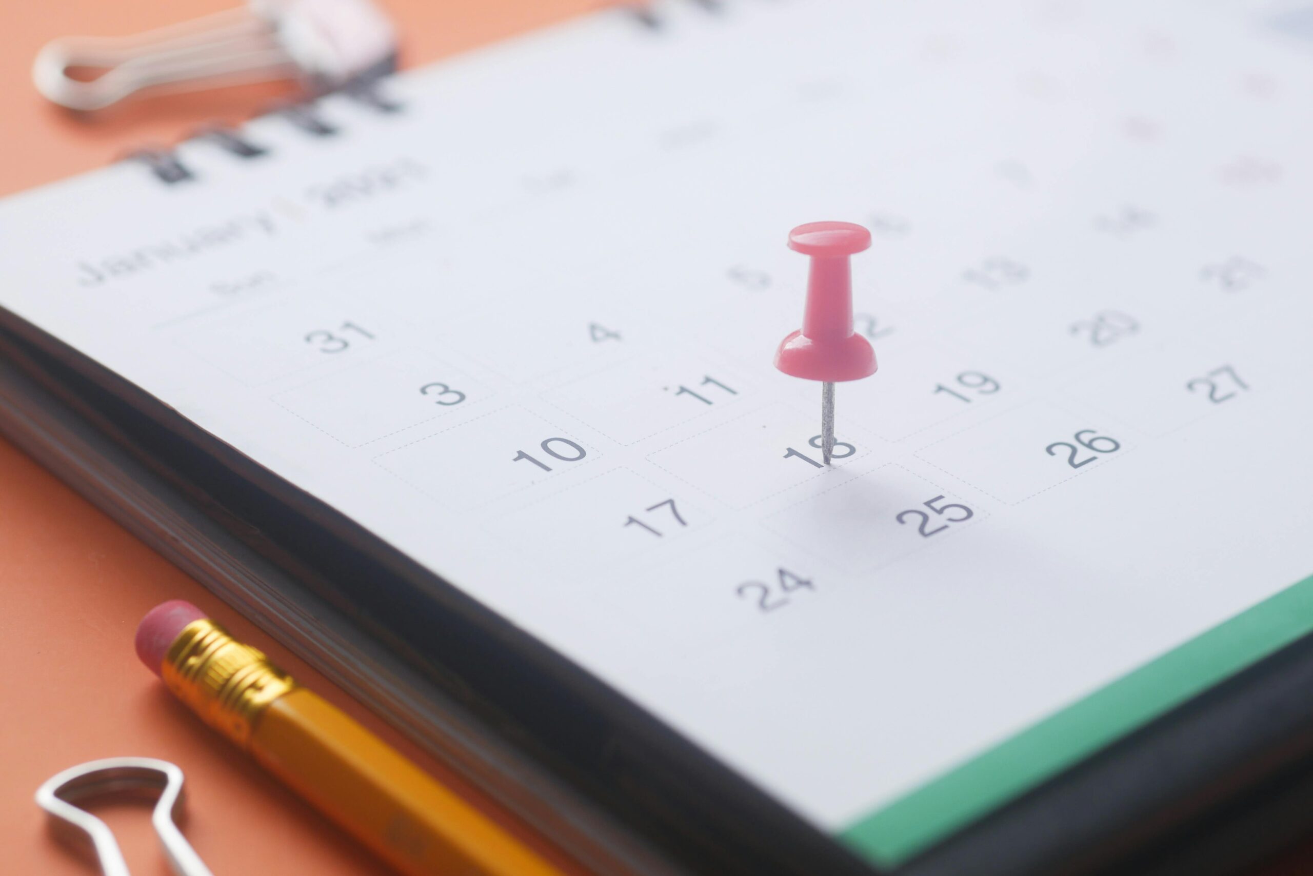 close-up of a calendar with a red pushpin marking an important date, symbolising school term planning for 2025.