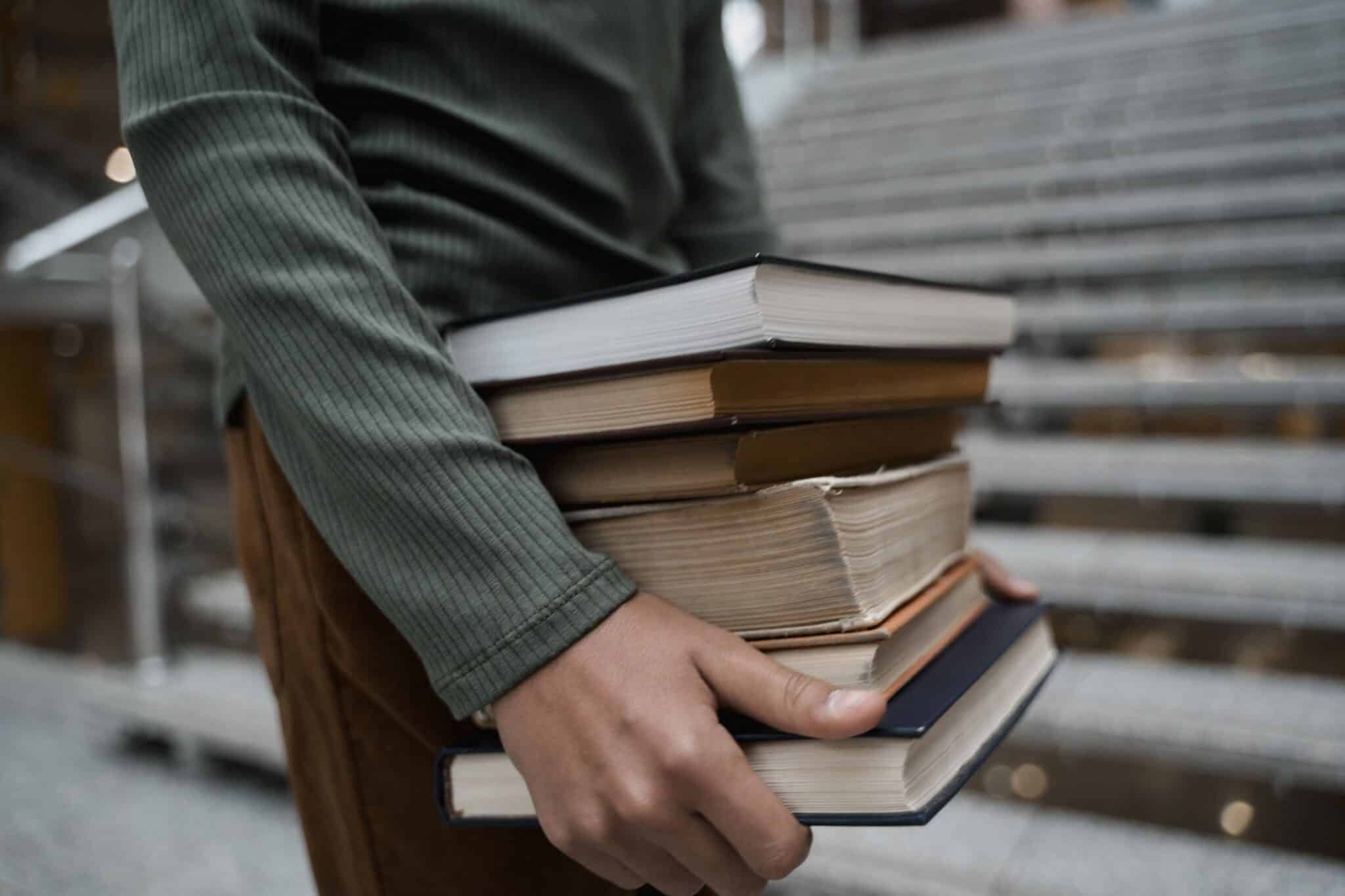 Student carrying a stack of textbooks, representing focused preparation for HSC and IB success during Term 3.