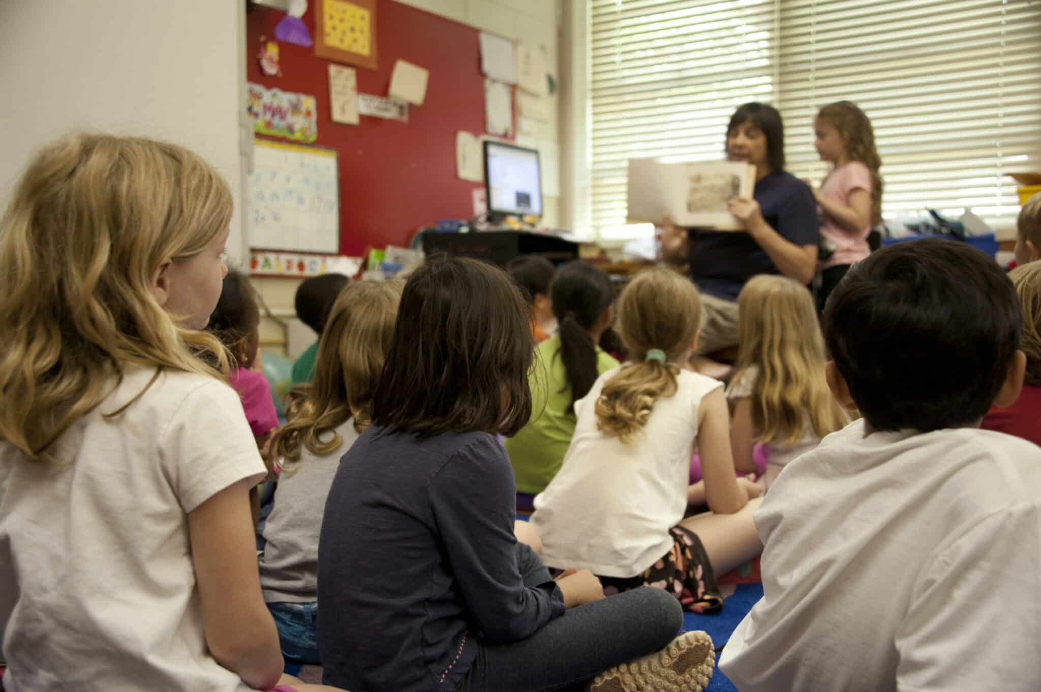 Primary school students listening to their teacher during a classroom lesson as they build confidence and learning skills in Term 3.