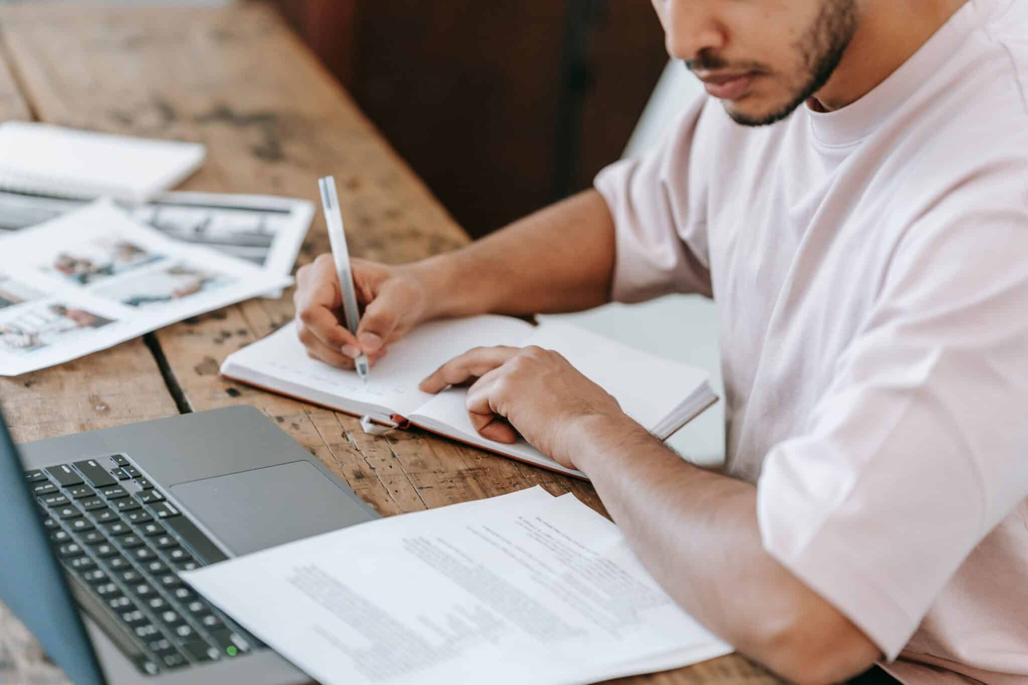 Student writing notes in a notebook beside a laptop while preparing for Term 3 VCE tutoring and exam revision.